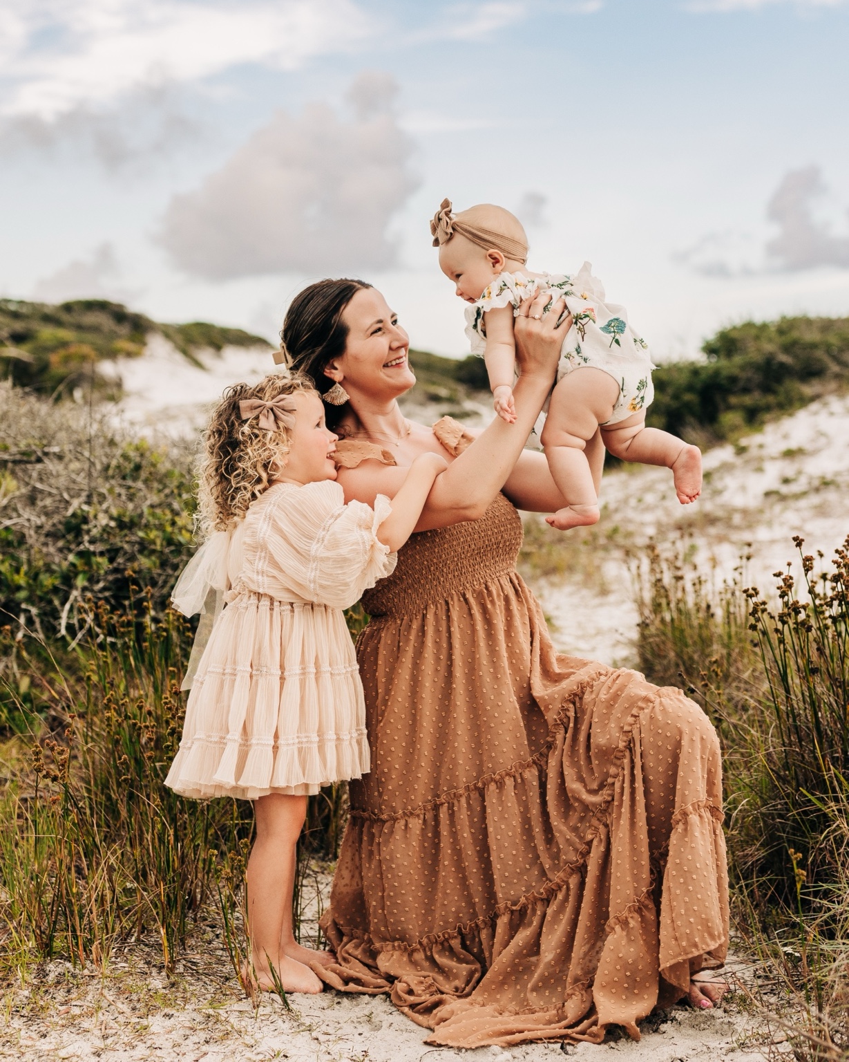 Mother and daughters wearing coordinated warm neutral dresses